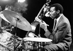 Jazztrummis spelar med cymbal och kontrabasist i bakgrunden